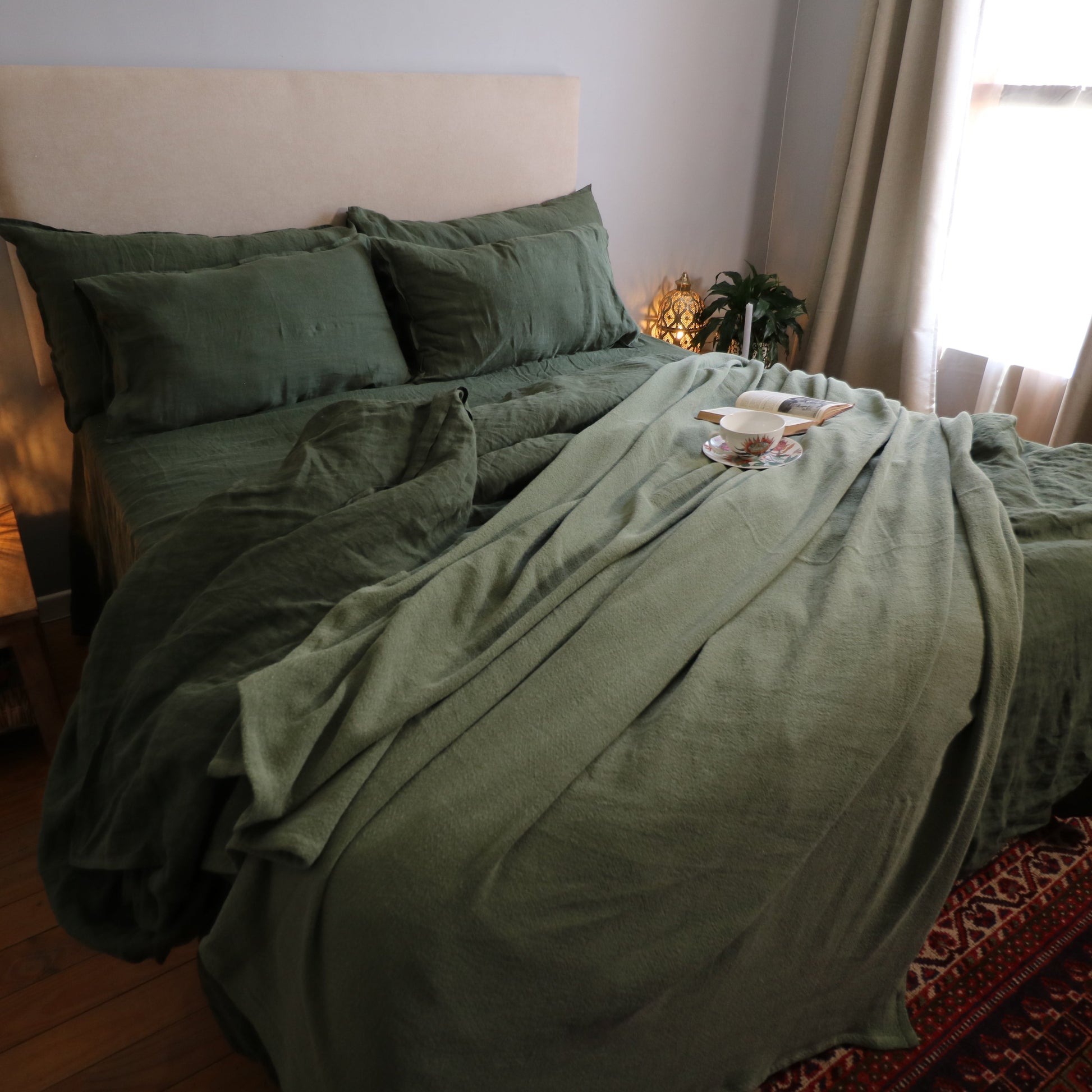 Bedroom with green bedding and a lamp on a nightstand.